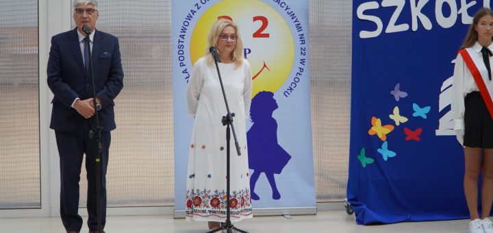 Pan dyrektor oraz zastępca dyrektora szkoły na tle napisu Witaj szkoło witają przybyłych na uroczystość pierwszoklasistów i ich rodziców.