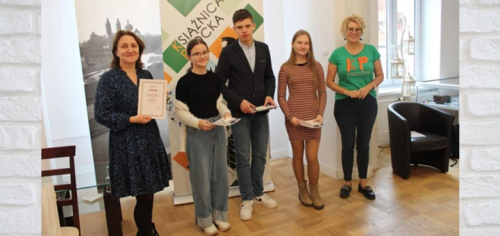 Drużyna z SP 22 pozuje do zdjęcia w Sali Kolumnowej Książnicy Płockiej. Dziewczyny w rękach trzymają książki – literackie menu konkursu, chłopiec miniaturę płockiego pomnika Marceliny Rościszewskiej.