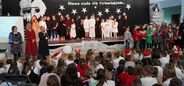 Na tle świątecznej dekoracji, na scenie znajdują się aktorzy, na sali widownia - uczniowie. Wicedyrektor szkoły p.M.Błachowicz i koordynatorzy p.E. Woźniak i p.M.Bartosiak