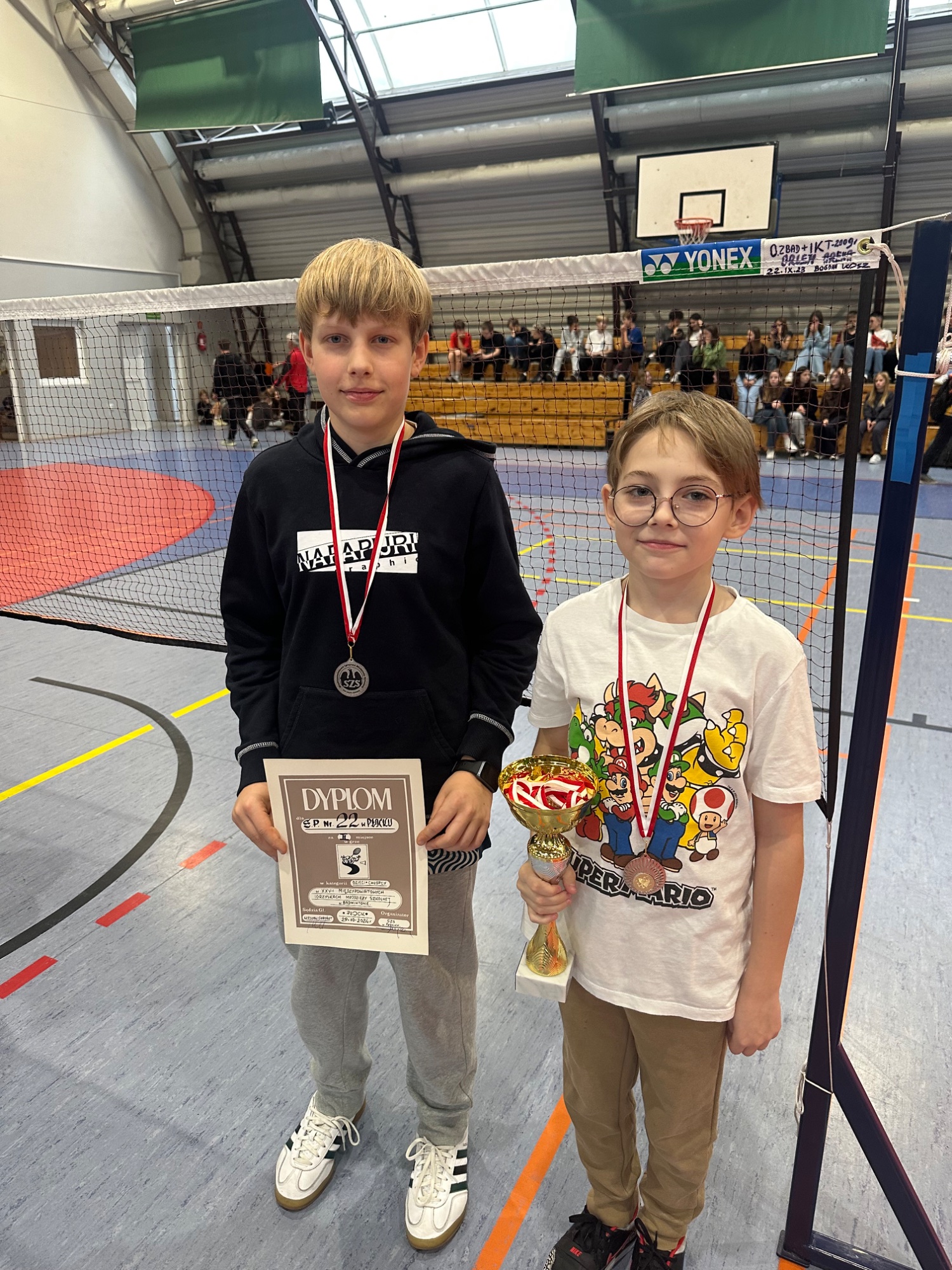 Zwycięzcy zawodów - Olgiert Byczek i Maksymilian Suliński w badmintonie z medalami i dyplomami.