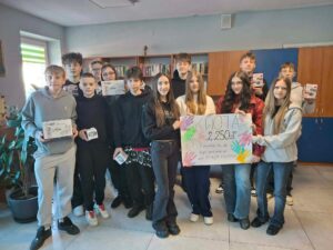 Przedstawiciele klas 8b i 8d prezentują zakupione dary i plakat informujący o kwocie, która została przeznaczona na zakup koncentratora tlenu, tj. 2 250 zł.